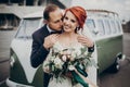Stylish groom gently kissing his happy bride in neck at retro car and smiling. emotional romantic moment, space for text. luxury Royalty Free Stock Photo
