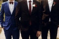 Stylish groom with groomsmen in suits with boutonniere posing, g