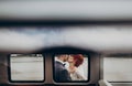 Stylish groom and happy bride embracing and gently kissing at retro car. emotional romantic moment, space for text. unusual view Royalty Free Stock Photo
