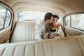 Stylish groom kissing his lovely beautiful bride in retro car, gentle moment Royalty Free Stock Photo