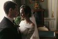 Stylish groom looking at his gorgeous bride in stylish dress with amazing bouquet  in luxury room in hotel. beautiful woman Royalty Free Stock Photo