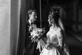 Stylish groom looking at his gorgeous bride in stylish dress with amazing bouquet  in luxury room in hotel. beautiful woman Royalty Free Stock Photo