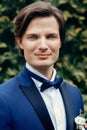 Stylish groom portrait in park. handsome man in blue suit smiling in spring park. gentleman or businessman at reception outdoors Royalty Free Stock Photo