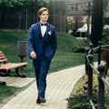 Stylish groom portrait in park. handsome man in blue suit walking in spring park. gentleman or businessman at reception outdoors Royalty Free Stock Photo