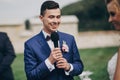 Stylish groom pronouncing vow to his beautiful bride during matrimony. Groom pronouncing speech and holding microphone. Beautiful Royalty Free Stock Photo