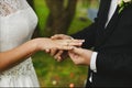 Stylish groom puts on the engagement ring on the finger of his beautiful bride at the wedding ceremony. Strong male Royalty Free Stock Photo