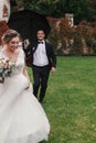 Stylish groom running under umbrella in rainy outdoor to Gorgeous bride and smiling. Sensual wedding couple having fun in rain. R Royalty Free Stock Photo