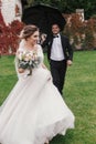 Stylish groom running under umbrella in rainy outdoor to Gorgeous bride and smiling. Sensual wedding couple having fun in rain. R Royalty Free Stock Photo