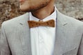 Stylish groom`s wooden bow tie, close up on background rocks at Royalty Free Stock Photo