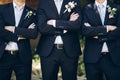 Stylish groom in suit posing with groomsmen in garden on wedding