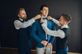 Stylish groomsmen helping happy groom getting ready in the morni