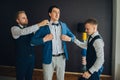 Stylish groomsmen helping happy groom getting ready in the morni