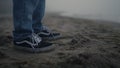 Stylish guy sneakers standing sandy beach. Man legs dancing on sea shore closeup Royalty Free Stock Photo