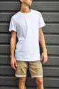 Stylish guy standing near the gray wall in a blank T-shirt Royalty Free Stock Photo