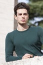 Stylish hair young man outdoors on the ledge, tight knit