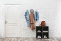 Stylish hallway interior with door, shoe rack and clothes hanging on wall Royalty Free Stock Photo