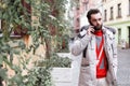 Stylish man with a beard in a winter jacket stands on the street talking on the phone. Portrait of a handsome man with a phone Royalty Free Stock Photo