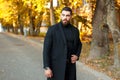 Stylish handsome man in a black coat walking outdoors Royalty Free Stock Photo