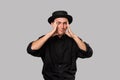 Stylish handsome man a black shirt and pork pie hat having problems  over grey background. Royalty Free Stock Photo