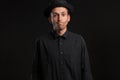 Stylish handsome man a black shirt and pork pie hat isolated over black background. Royalty Free Stock Photo