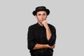 Stylish handsome man a black shirt and pork pie hat isolated over grey background Royalty Free Stock Photo