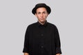 Stylish handsome man a black shirt and pork pie hat isolated over grey background Royalty Free Stock Photo