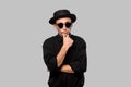 Stylish handsome man a black shirt and pork pie hat  over grey background Royalty Free Stock Photo