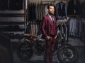 Handsome man with a stylish beard and hair dressed in vintage red suit posing near retro sports motorbike at men`s Royalty Free Stock Photo