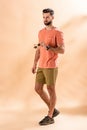 Stylish handsome man posing in shorts and summer t-shirt holding sunglasses Royalty Free Stock Photo