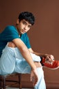 Stylish handsome mixed race man posing on studio sitting on a chair looking to camera Royalty Free Stock Photo