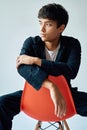 Stylish handsome young man posing on studio sitting on a chair on white background Royalty Free Stock Photo