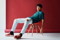 Stylish handsome young man relax and posing on studio sitting on a chair looking to camera. Royalty Free Stock Photo