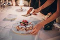 Stylish happy bride and groom cutting together wedding cake with fruits at wedding reception outdoors in the evening. Couple hands Royalty Free Stock Photo