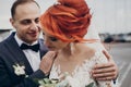 Stylish happy bride and groom gently hugging at retro car and smiling. emotional romantic moment, space for text. luxury wedding Royalty Free Stock Photo