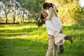 Stylish happy bride, groom hold picked up in hands and dancing. The groom raised and spins bride. Newlyweds kissing. On Royalty Free Stock Photo
