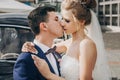 Stylish happy bride and groom kissing at old black retro car. Gorgeous wedding couple of newlyweds embracing after wedding Royalty Free Stock Photo