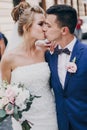 Stylish happy bride and groom kissing in old european city street. Gorgeous wedding couple of newlyweds embracing  outdoors. Royalty Free Stock Photo