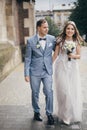 Stylish happy bride and groom walking on background of church in sunny street. Provence wedding. Beautiful emotional wedding Royalty Free Stock Photo