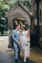 Stylish happy bride and groom walking on background of church in sunny street. Provence wedding. Beautiful emotional wedding Royalty Free Stock Photo