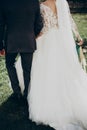 Stylish happy bride and groom walking in yard and holding hands at wedding ceremony. emotional moment, space for text. luxury Royalty Free Stock Photo