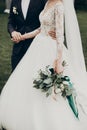 Stylish happy bride and groom walking in yard and holding hands at wedding ceremony. romantic moment, space for text. luxury Royalty Free Stock Photo