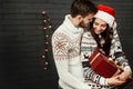 Stylish happy couple with big red present smiling gently hugging