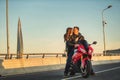 Young couple riding the red sports motorcycle at bridge on sunrise Royalty Free Stock Photo