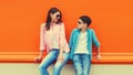 Stylish happy smiling mother with son teenager look at each other posing together in sunglasses, checkered shirts, jeans in the