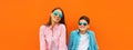 Stylish happy smiling mother with son teenager posing together in sunglasses, checkered shirts, jeans in the city on orange Royalty Free Stock Photo