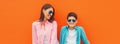 Stylish happy smiling mother with son teenager posing together in sunglasses, checkered shirts, jeans in the city on orange Royalty Free Stock Photo