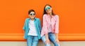 Stylish happy smiling mother with son teenager posing together in sunglasses, checkered shirts, jeans in the city on vivid orange Royalty Free Stock Photo