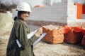 Stylish happy woman architect with blueprints and plans at construction site. Young female engineer or construction worker in Royalty Free Stock Photo