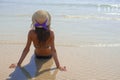 Stylish happy young woman relaxing on beach. girl sitting and tanning on beach near sea with waves, sunny warm weather. Summer Royalty Free Stock Photo