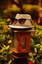 The stylish hat, muff,napper with sunglasses,spectacles is standing on the lamp with warm tones in summer times